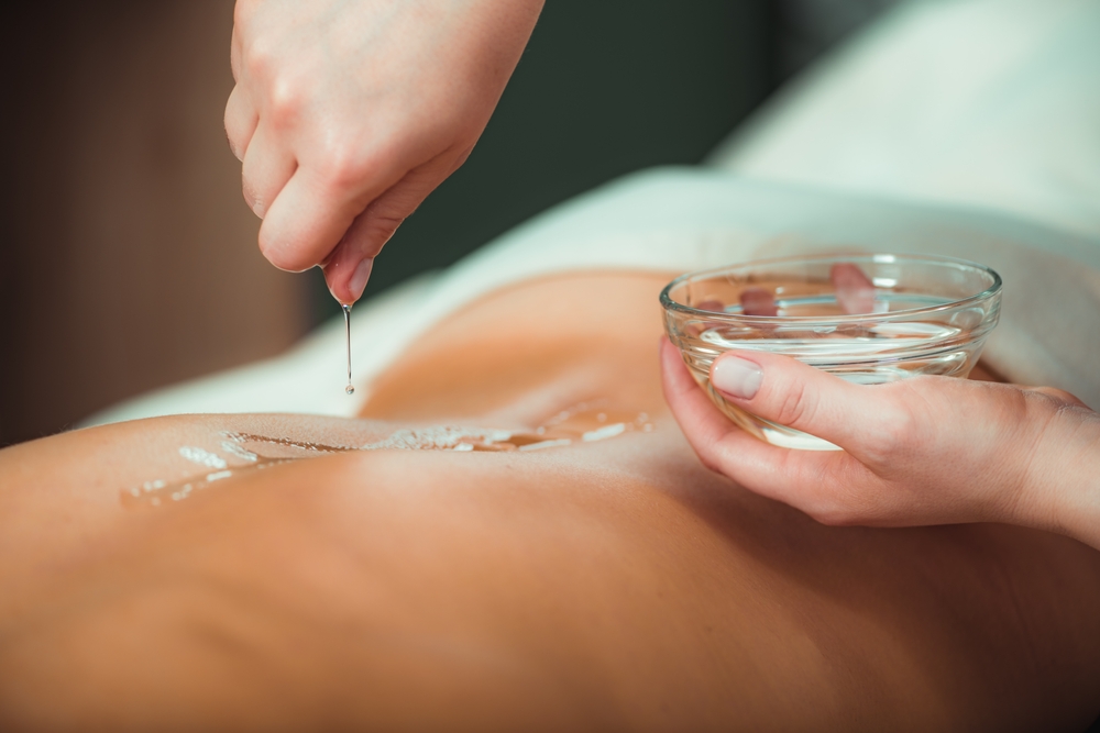 massage,oil.,therapist,pouring,aromatic,massage,oil,onto,womans,back